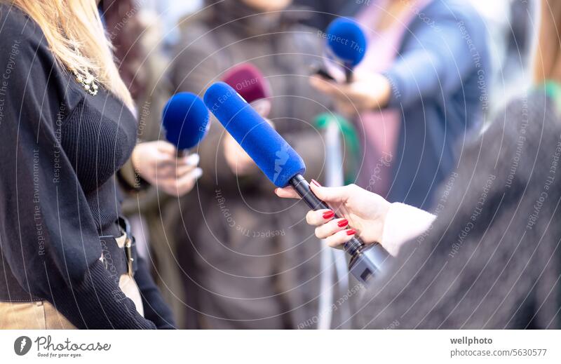 Press, news conference or media scrum, female journalist holding microphone, other reporters with microphones in the background press media event