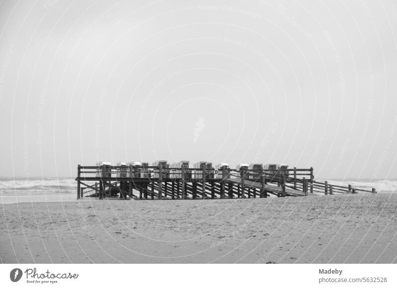 Beach chair platform at Noah's Ark at the end of the pier on the beach of the seaside resort of St. Peter-Ording in the district of Nordfriesland in Schleswig-Holstein in the fall on the North Sea coast in black and white