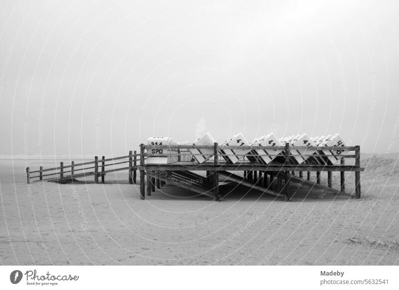 Beach chair platform at Noah's Ark at the end of the pier on the beach of the seaside resort of St. Peter-Ording in the district of Nordfriesland in Schleswig-Holstein in the fall on the coast of the North Sea in black and white