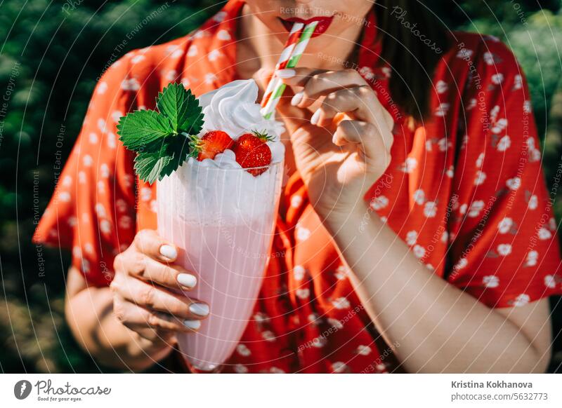 Pretty woman drinking strawberry milkshake cocktail with straw, nature backdrop beautiful beverage breakfast bright cheerful delicious dessert diet eating