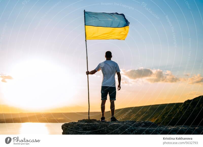 Ukrainian man with national flag on summer sky, high rock, wide river Dniester ukraine war conflict freedom independence ukrainian army military patriot