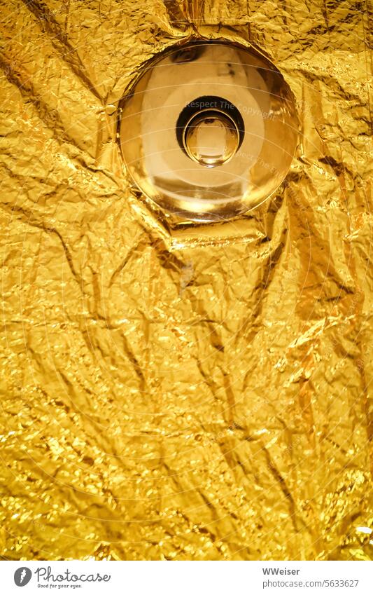 A golden button in a surface clad in gold. What does it do? knob Gold Packing film leaf gold Noble Metal Glimmer warm Pushing