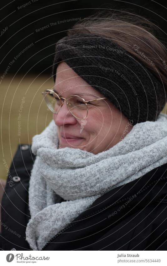 Beautiful woman grins Woman Grinning pleased Good mood Winter out Cold wrapped winter clothes Scarf Headband Eyeglasses Gold Gray Black cute pretty