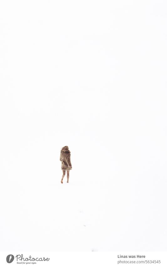 All is white, though all is not calm. In this cold, white snow blizzard, you can barely see a thing. Only a barefoot girl with fake fur is running through this endless white landscape. It's a minimalistic image of winter beauty.