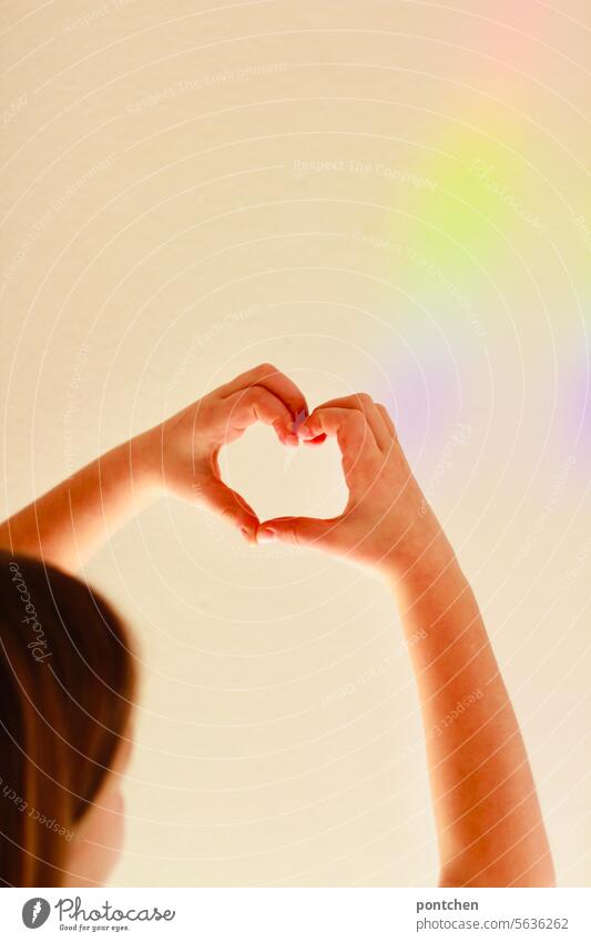 a child forms a heart with his hands in front of a strip of light in rainbow colors. love, joy, happiness Beam of light Rainbow Child Hope Joy Happy Light hair