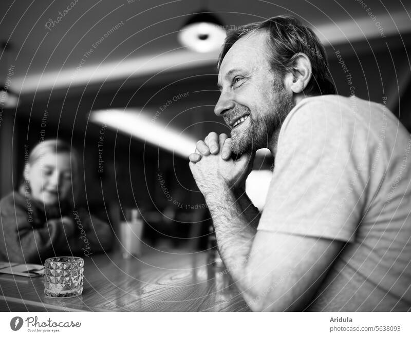 Cheerfully smiling man and a child sitting at a table b/w Man Laughter kind listen Child Table Sit convivial gathering Sociable Together Joy Smiling Restaurant
