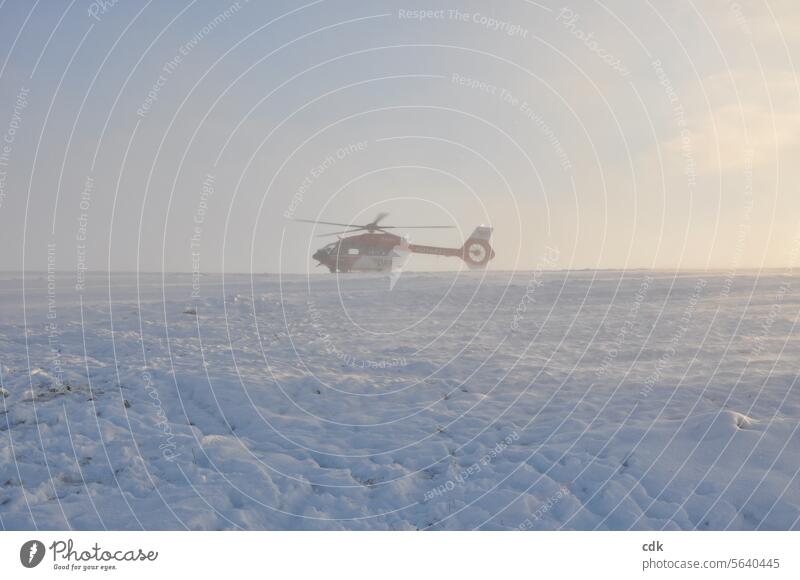 An air rescue helicopter has landed on the mountain. The swirling fresh snow slowly settles and bathes the scene in a soft light. Helicopter Technology Aviation