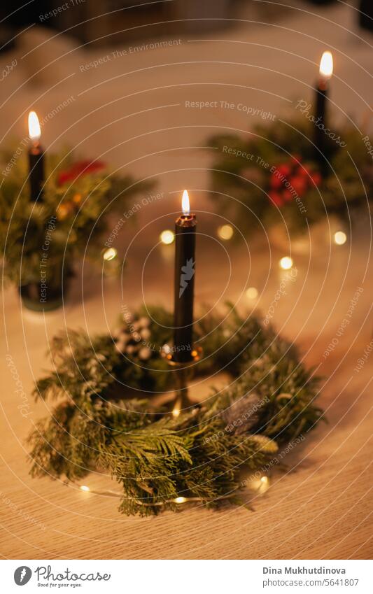 Christmas floral arrangement with black burning candle. Centerpiece festive decoration with conifer branches and red berries. candles lights centerpiece berry