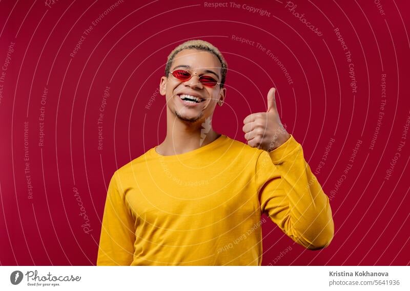 Positive man makes hand sign like, thumbs up gesture. Happy student guy on red good ok okay yes choice agreement satisfaction symbol approve leisure lifestyle