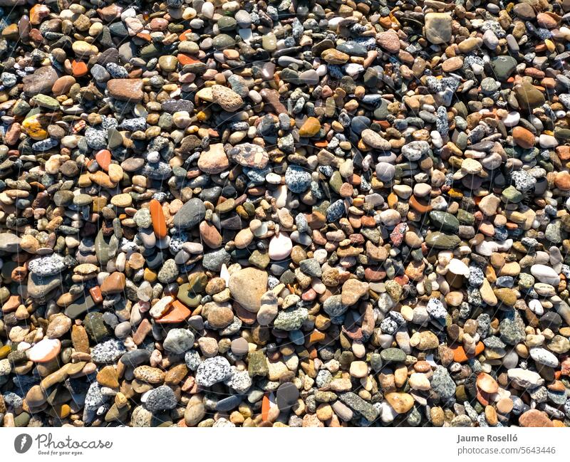 background of many small river stones of various colors, stones recently wet by the river water funds roof textured space rock mineral gray grey structure