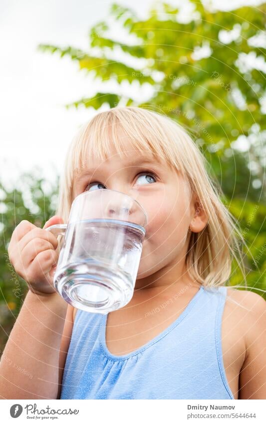 Child drinking water outdoors 4-5 years aqua beverage blonde blue caucasian child childhood clean clear closeup cup drinkable fresh garden girl glass hand