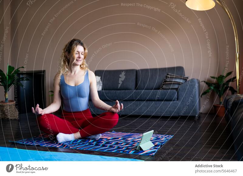 Young woman practicing yoga at home on a mat smartphone pose serene colorful cozy living room fitness wellbeing health exercise peace meditation lifestyle