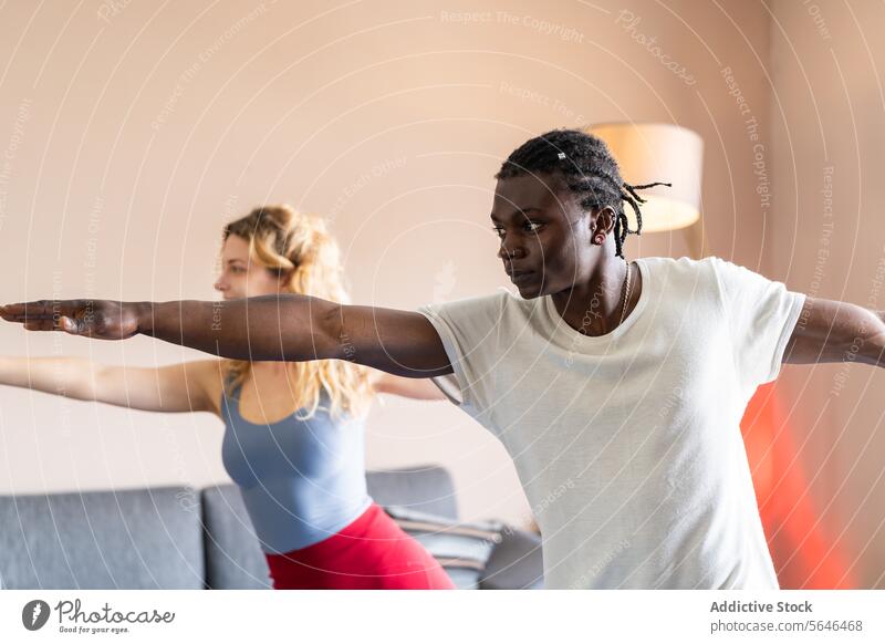 Diverse duo practicing yoga together indoors practice diversity exercise fitness health concentration pose wellness balance harmony lifestyle man woman room