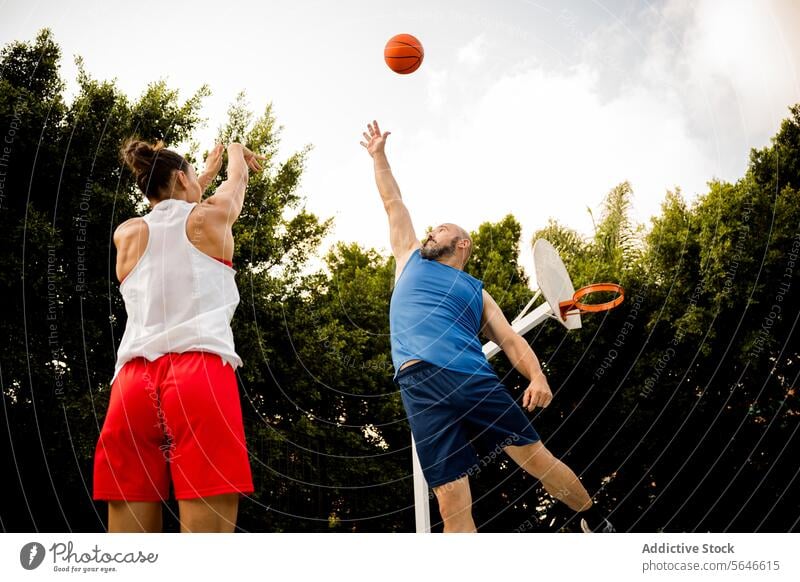 Determined man and woman playing basketball on court Sportspeople Basketball Throw Play Shoot Hoop Jump Defend Sportsman Ball Athlete Man Woman Sports Ground