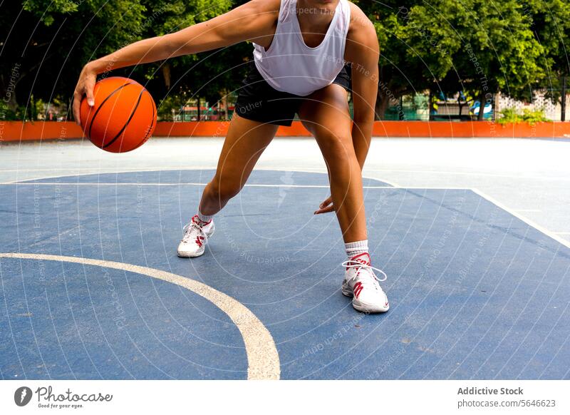 Crop unrecognizable sporty female in activewear dribbling while playing basketball on court during sunny summer day Sportswoman Basketball Play Court Dribble