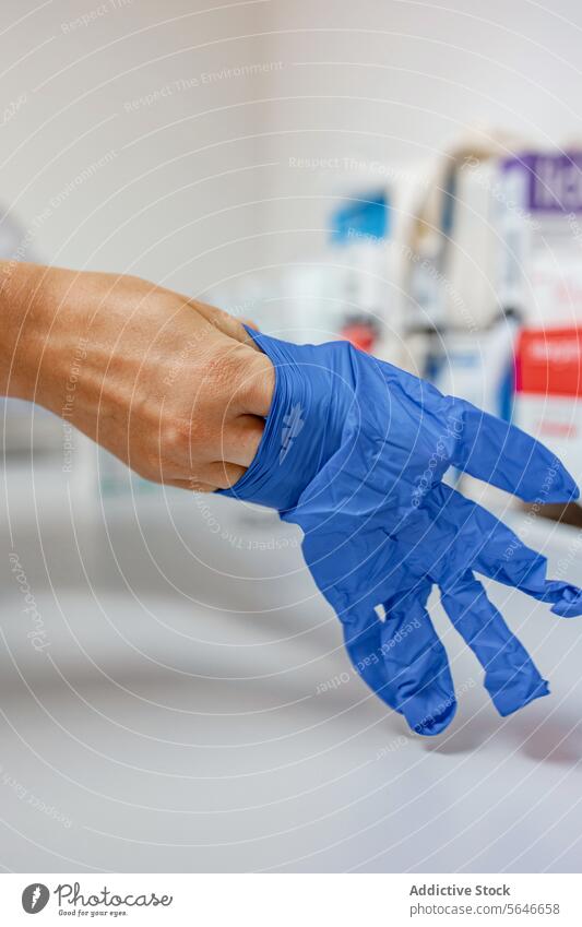 Crop medic wearing blue gloves in hand against blurred person doctor hospital clinic medical corridor demonstrate medicine health care professional uniform