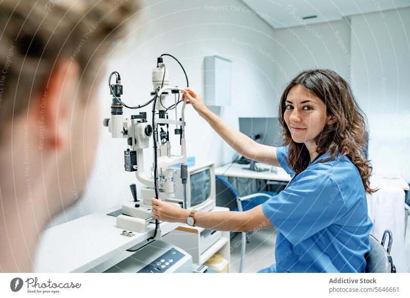 Happy young woman doctor standing near slit lamp biomicroscope with anonymous man in hospital smile happy uniform stethoscope patient female professional