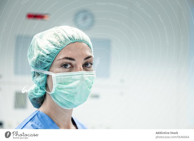 Female doctor in protective mask and cap looking at camera woman hospital surgeon clinic uniform health care professional specialist prevent medicine medical