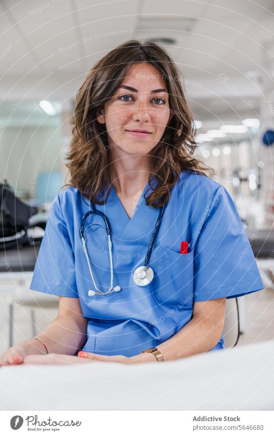 Happy young woman doctor in uniform sitting at table in hospital portrait smile professional stethoscope work health care job female happy wristwatch therapist