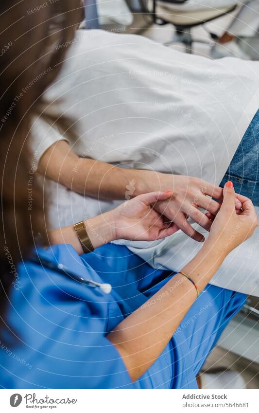 Unrecognizable woman doctor holding hand of blurred man patient lying on bed holding hands uniform check up professional hospital male female specialist
