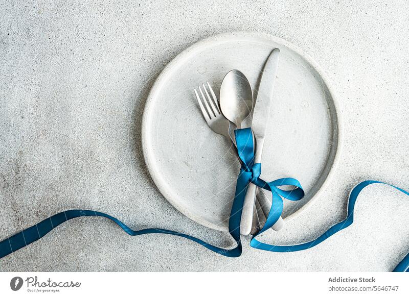 Top view of Minimalist Easter Table Decor minimalist table decor blue ribbon concrete backdrop simplicity texture stylish rough texture ribbon-tied cutlery