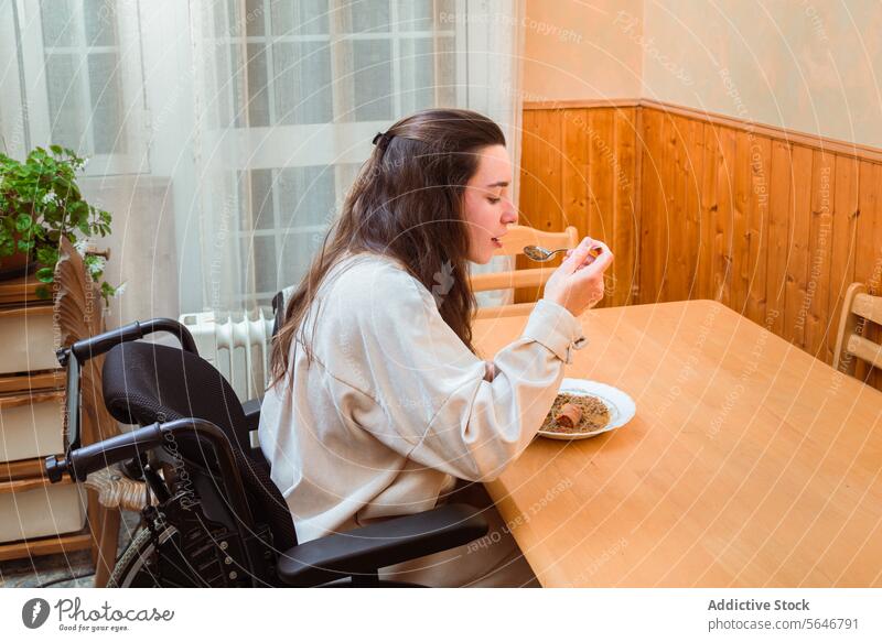 Woman enjoying Meal at Home in Wheelchair woman wheelchair dining home meal enjoyment accessibility table eating content independence adapted lifestyle food