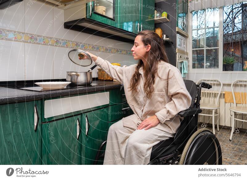 Woman in Wheelchair Cooking in Accessible Kitchen woman wheelchair cooking kitchen accessibility invalid adaptation independence home interior lifestyle