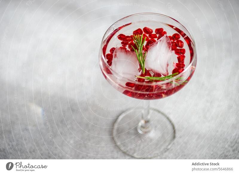 Pomegranate gin tonic placed in concrete background cocktail pomegranate seed rosemary glass alcohol beverage drink ice grey textured mixology bar aperitif