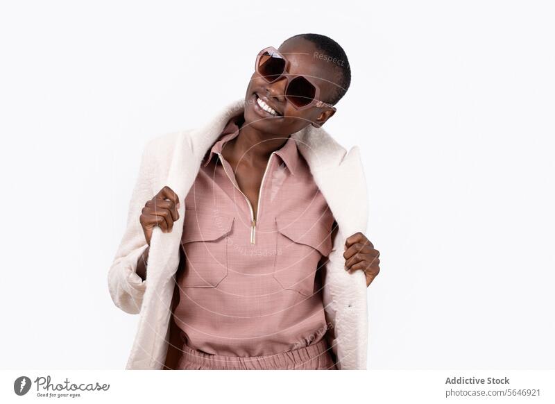 Cheerful young African American female in trendy long coat and sunglasses looking at camera while standing on white background Woman Style Trendy Outfit Long