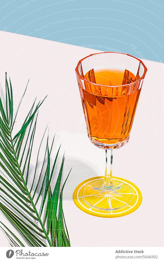 Elegant Cocktail Glass on a Vibrant Backdrop cocktail glass amber crystal citrus coaster palm frond pastel backdrop drink stylish vibrant elegant shadow table