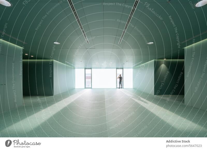 Anonymous man with smartphone standing in empty green room with glass doors in modern hospital Hospital Green Empty Door Wall Ceiling Interior Modern Medical