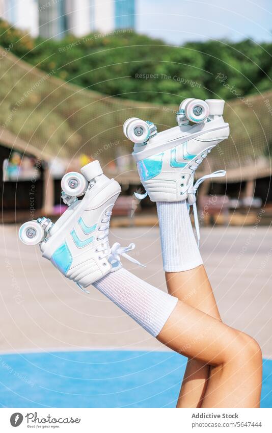 Crop female skater raising legs with roller sneaker skates park person leg raised sports ground active training practice sneakers healthy lifestyle footwear