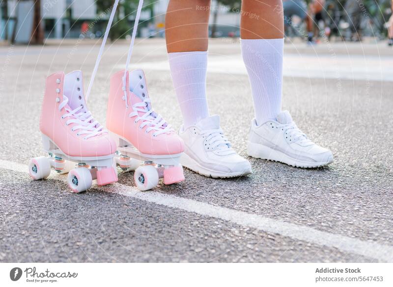 Crop woman in trendy sneakers standing by pink quad skates on street skateboard teenage leg road city footwear sock style female young casual cool sporty