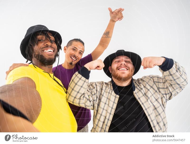 Three friends taking a playful selfie together friendship men young adult cheerful smile happy pose camera peace sign white background casual joy fun