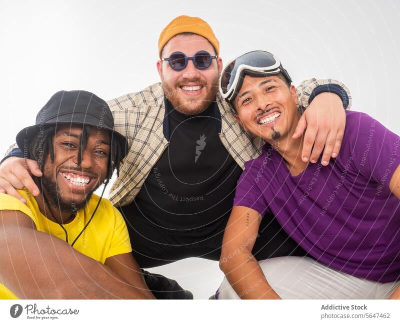 Three happy friends enjoying a casual gathering friendship men smile cheerful embrace camaraderie white backdrop diverse stylish attire multiracial happiness
