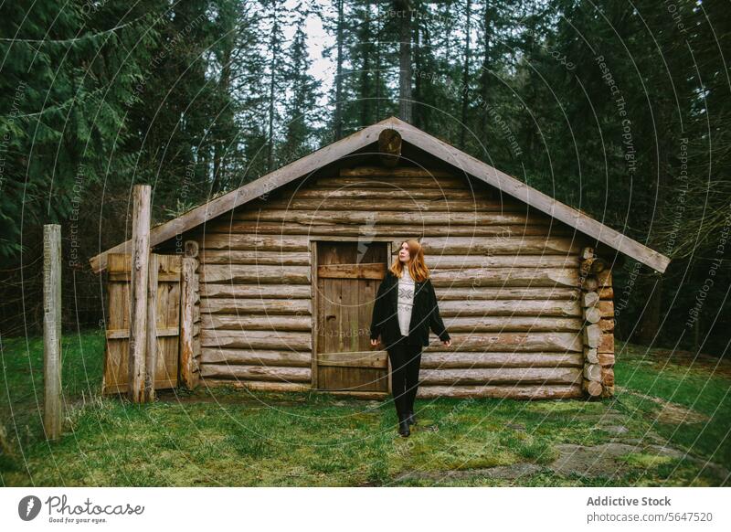 Woman standing by a rustic log cabin in the woods woman forest clearing vancouver island british columbia canada tranquil exploration outdoors nature wooden
