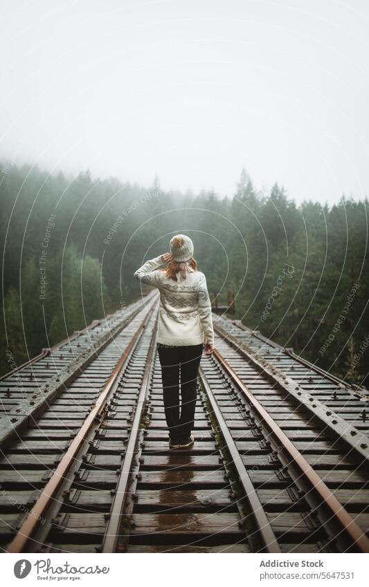 Back view of solitary woman in journey on a foggy Vancouver Island train track person railway mist vancouver island back view british columbia canada