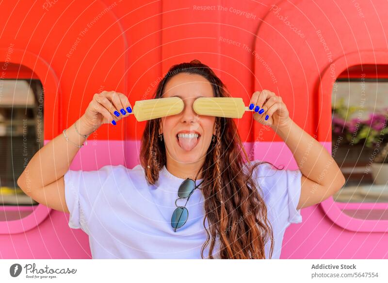 Carefree woman with ice creams at summer popsicle playful tongue carefree fun enjoy covering happy brunette sticking red pink wall eyes white dessert sunglasses