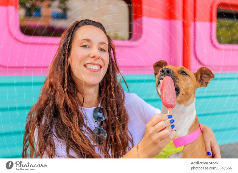 Smiling female with long brown hair and pet woman dog popsicle feeding happy portrait brunette friend ice cream summer blurred background beautiful smiling