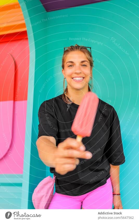Portrait of happy woman with frozen dessert popsicle smile portrait beautiful cream ice cream wall blue standing enjoy looking at camera lifestyle black