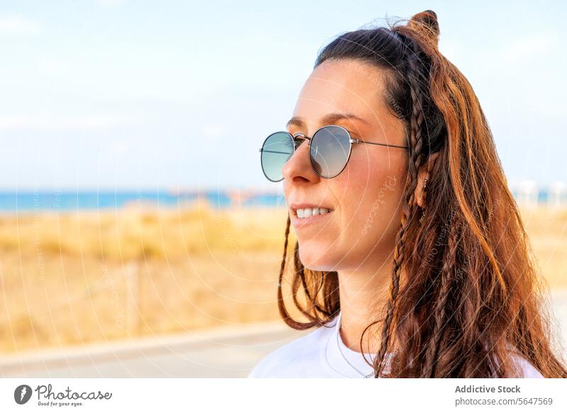 Beautiful female brunette with bun and braids woman smiling sunglasses brown attractive hair long beautiful copy space blurred background stylish lifestyle