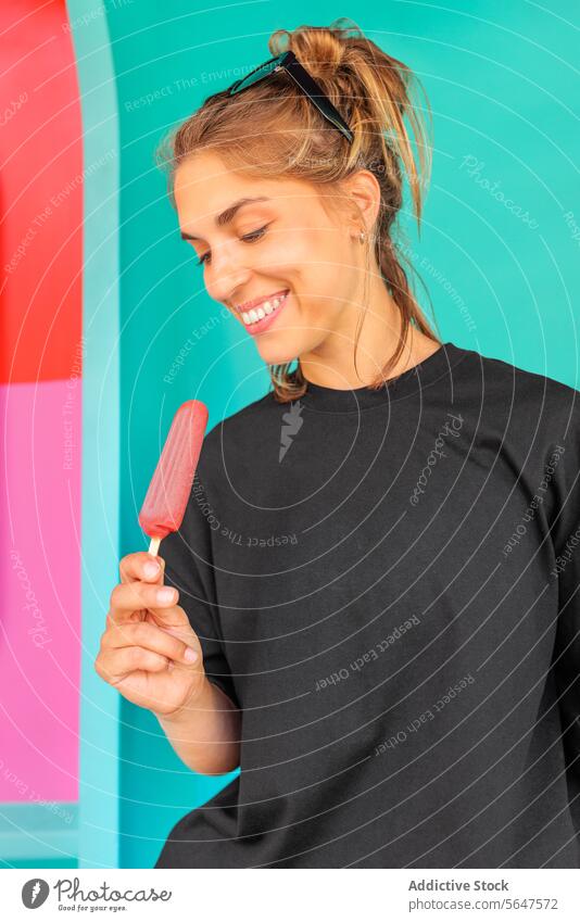 Portrait of happy woman with frozen dessert popsicle smile portrait beautiful cream ice cream wall blue standing enjoy lifestyle cheerful black soft focus