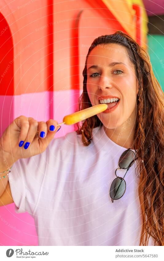 Happy woman with long brown hair and sunglasses popsicle eating portrait ice cream beautiful brunette blurred background happy looking at camera biting playful