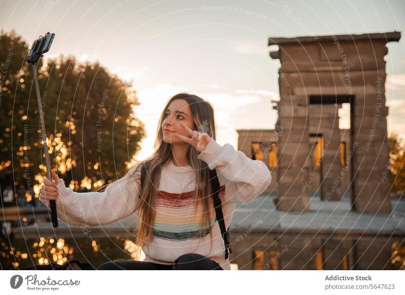 Young woman capturing sunset moments with a selfie stick in Debod Temple in Madrid monopod temple golden hour historic backdrop young female photography travel