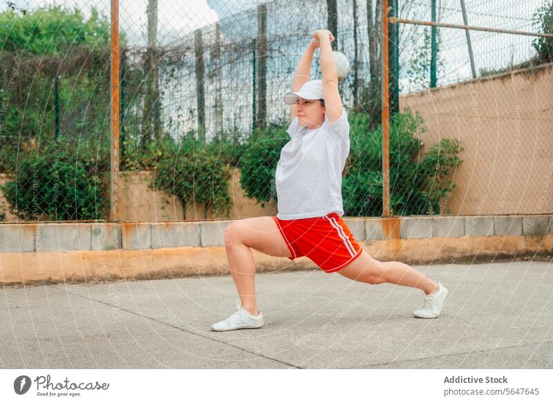 Active Woman Performing Stretching Exercise Outdoors woman stretching exercise outdoors sportswear health fitness lifestyle tennis court active