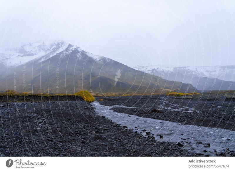 Misty Icelandic landscape with mountains and stream iceland tranquil fog mist shrouded black pebble background nature outdoor serene travel destination scenic