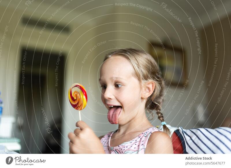 Young girl enjoying colorful lollipop at home candy child sweet treat snack dessert happiness enjoyment delight playful sugar taste tongue fun swirl kid indoors