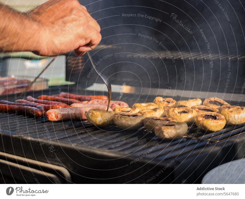Crop cook grilling sausages and hot dogs on barbecue chef restaurant pan fry delicious food meal tasty roast yummy fork dish palatable delectable hand