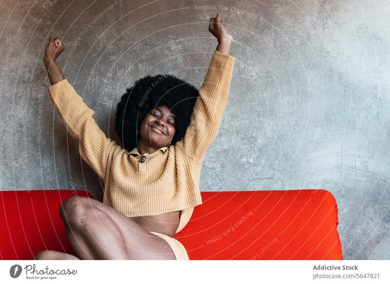 Smiling black woman stretching after waking up wake up home weekend awake relax comfort enjoy arms raised female african american morning afro eyes closed
