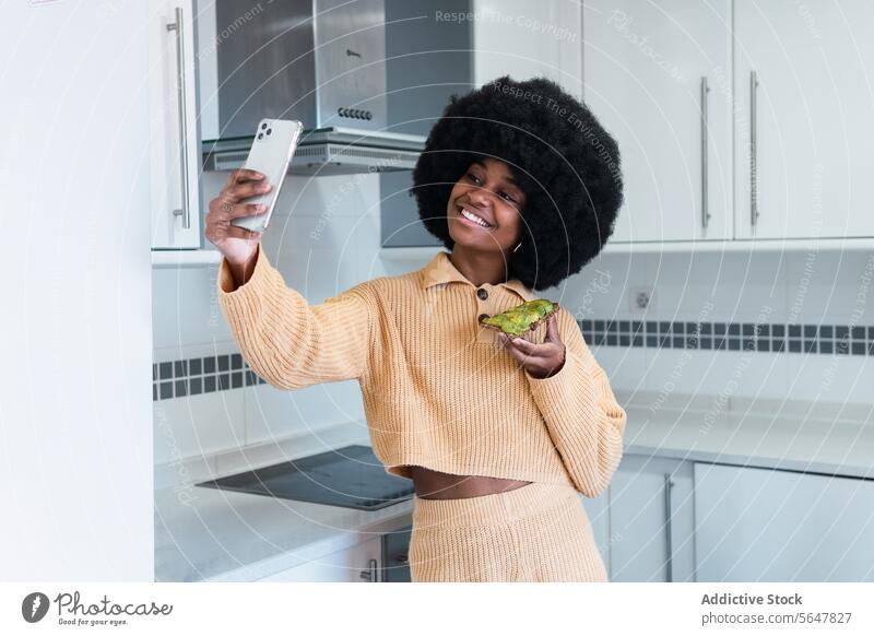 Smiling black female taking selfie with toast woman breakfast healthy lifestyle kitchen smartphone self portrait avocado using morning african american afro